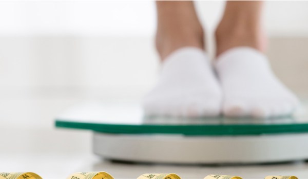 Person checking weight on a scale, questioning calorie deficit.